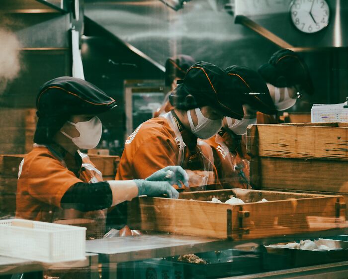 Workers in masks and gloves preparing food, emphasizing places that failed health inspections.