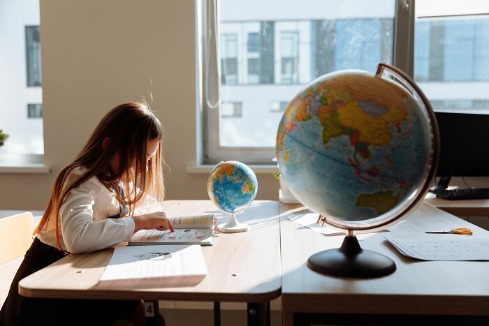 Young student studying a book with a globe nearby, representing general knowledge questions from easy to hard levels. Young student studying a book with a globe nearby, representing general knowledge questions from easy to hard levels.