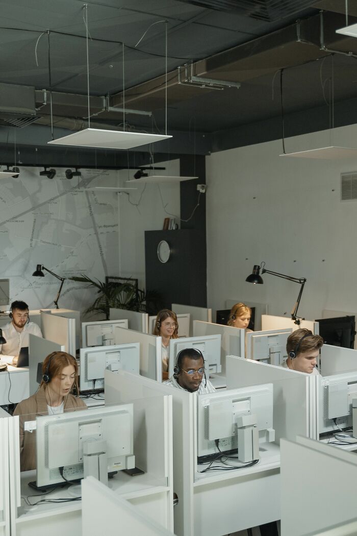 A busy office environment with several employees wearing headsets, working at their desks, reflecting a final day at work.