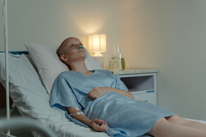 Patient with an IV and oxygen tube lying in a hospital bed as part of the medical industry.