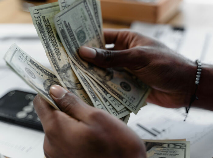 Close-up of a person counting several $20 bills, highlighting the topic of child support payments. Close-up of a person counting several $20 bills, highlighting the topic of child support payments.