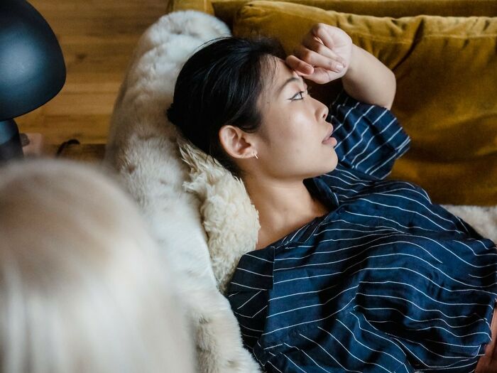 Woman lying on a couch, deep in thought about unhinged therapist moments and personal recovery.