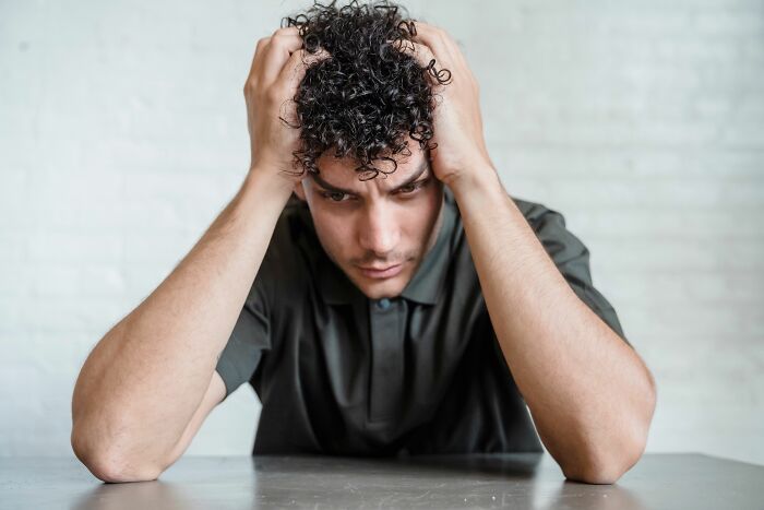 A man looking distressed with hands in his hair, representing easily missed psychological red flags.