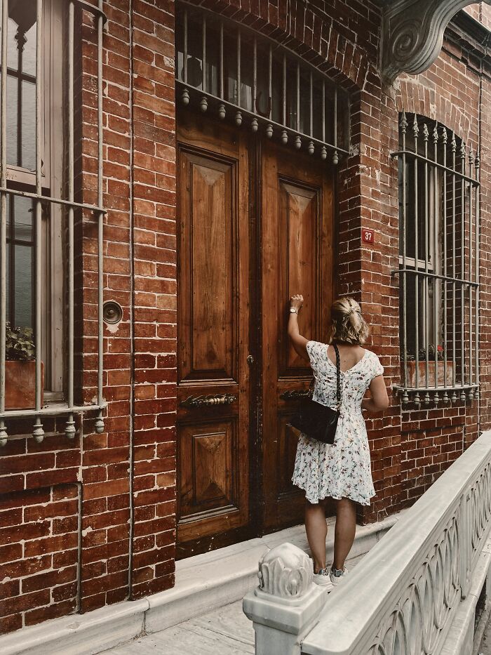 A woman knocking on a wooden door, potentially related to small cheating red flags.