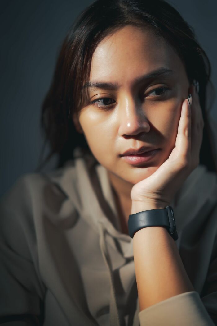 A thoughtful woman resting her face in her hand, contemplating secrets she wasn't supposed to know.