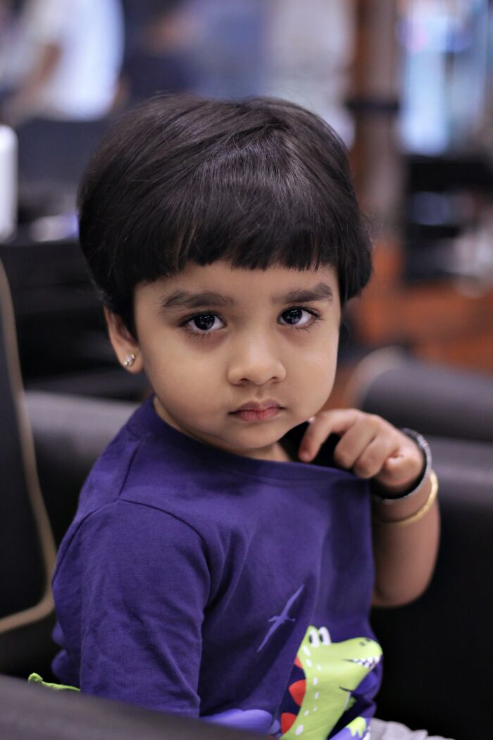 A serious-looking child with dark hair and a purple shirt, reflecting the experiences of parents terrified of their own children.