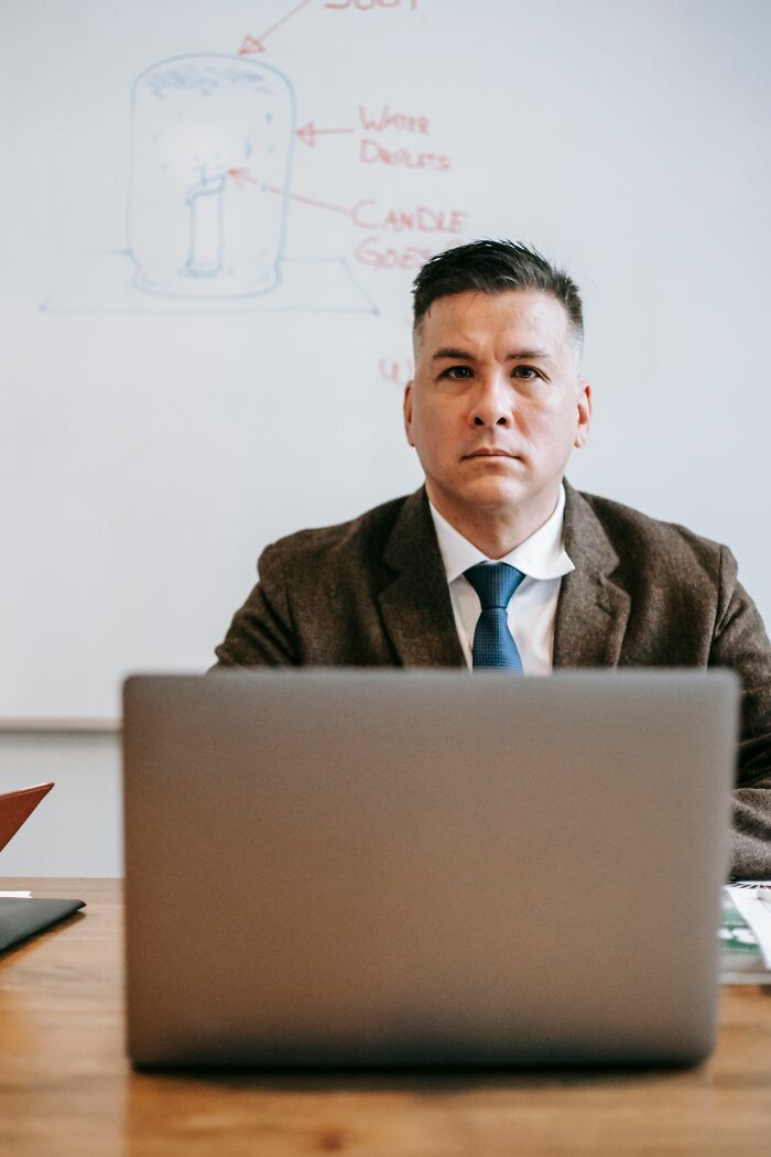 A man in a suit looking seriously at the camera, embodying the spirit of an office story.