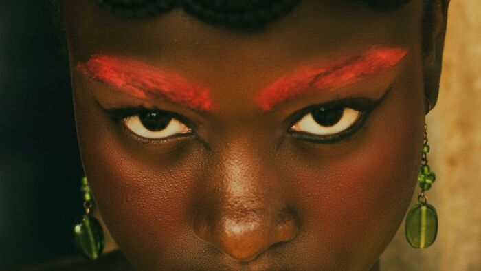A close-up of a person's eyes with red painted brows and green earrings. Test your screen knowledge by recognizing characters' eyes from films and shows. A close-up of a person's eyes with red painted brows and green earrings. Test your screen knowledge by recognizing characters' eyes from films and shows.