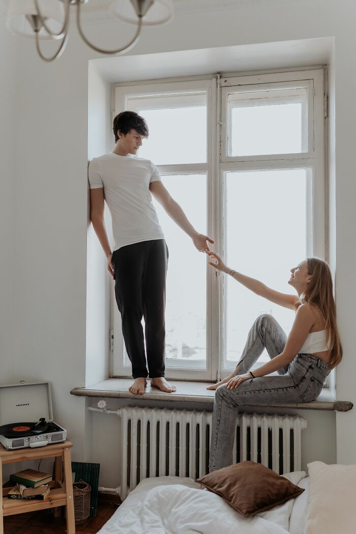 A young couple interacting by a window, emphasizing things to know before getting married.