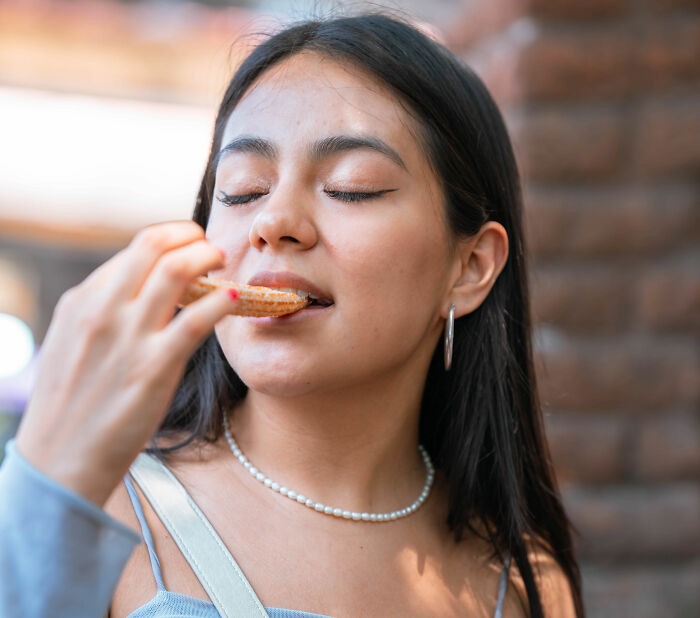 A woman savoring a churro, eyes closed in delight, experiencing a moment of instant justice.
