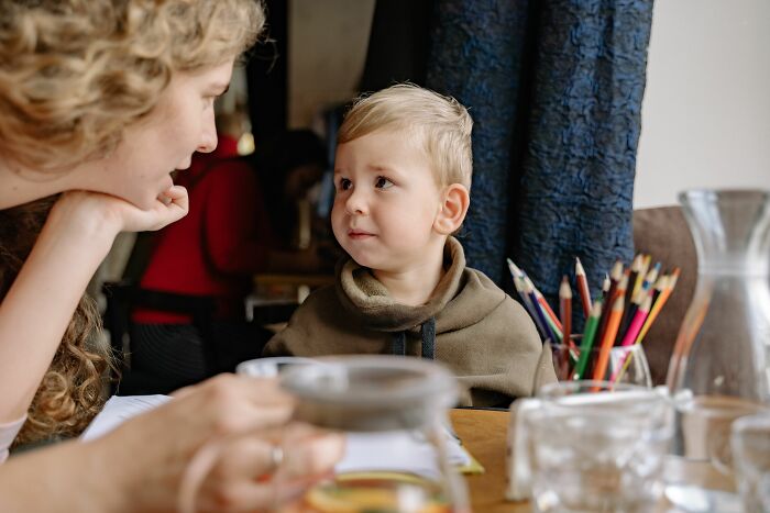 A young boy looks intently at his mother across a table with colored pencils, capturing moments of parents terrified.