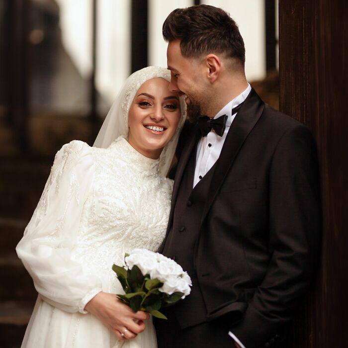 A happy bride in a white dress and groom in a tuxedo smiling, highlighting things to know before getting married.