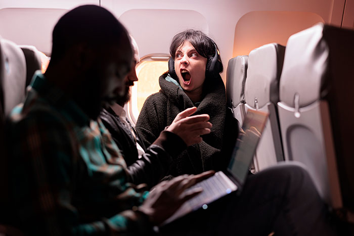 A woman on an overnight flight reacts with a tantrum, physically stopping a stranger from reclining.