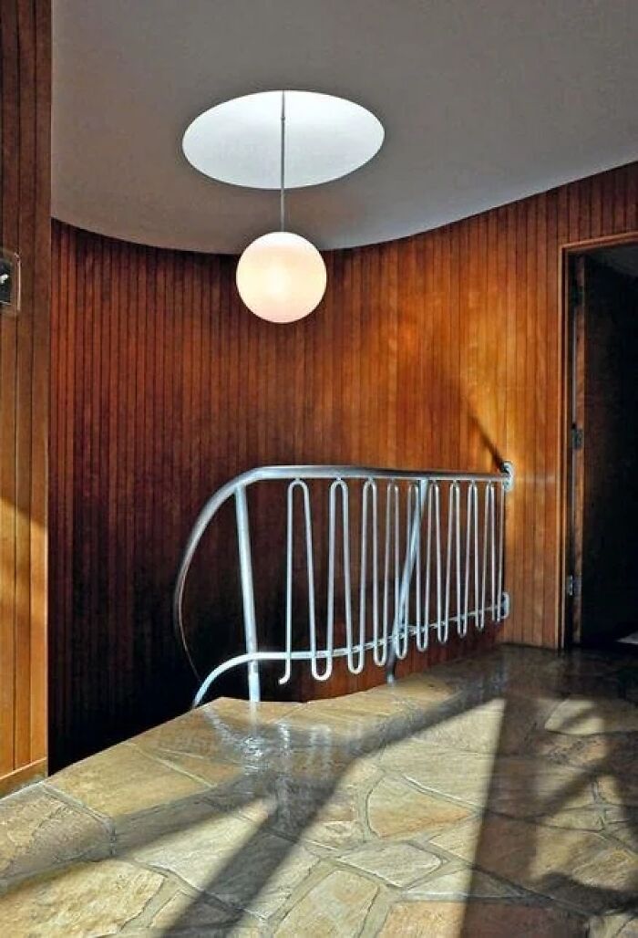 A view of a curved staircase with a unique white railing and wooden wall paneling, highlighting historic interiors.