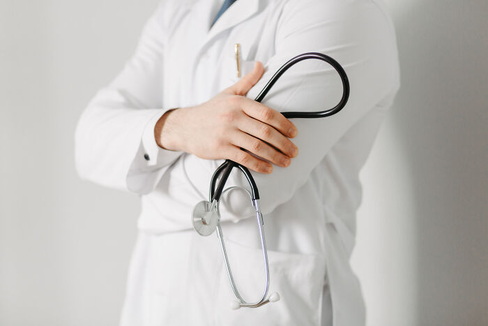 A doctor in a white coat holding a stethoscope, representing a professional aspect of corporate practices.
