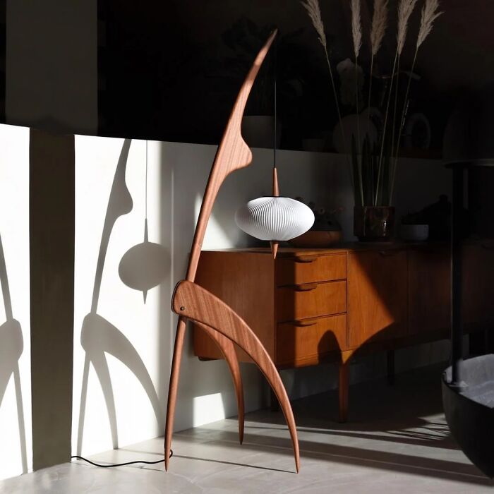 Remarkable Designs: A unique, tall wooden floor lamp with a pleated white shade, showcasing iconic furniture design.
