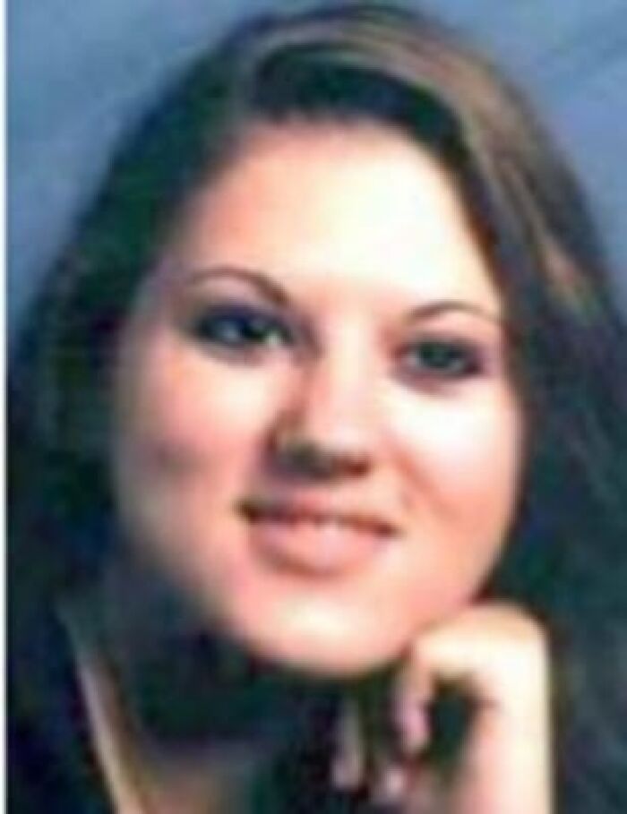 A young woman with long dark hair, smiling slightly with her hand to her chin, in a story about unsolved mysteries.
