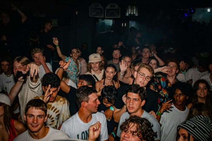 A crowded, dark club with people looking uneasy, highlighting a potential 'we need to leave now' scenario.