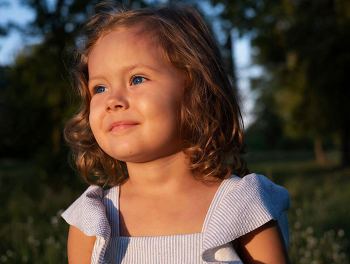 Portrait of a smiling blue-eyed kid, a mixed-race child, against a soft outdoor background. Portrait of a smiling blue-eyed kid, a mixed-race child, against a soft outdoor background.