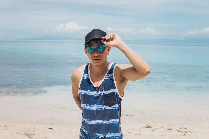 A man in sunglasses and a cap on a beach, an international partner encountering culture shocks.