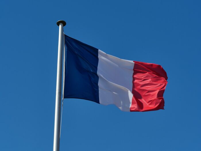 A French flag waving against a clear blue sky, relating to historical myths.