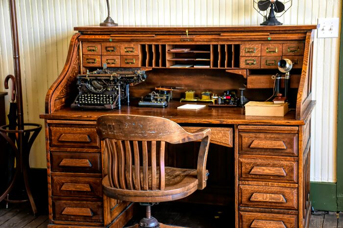 An antique wooden roll-top desk with a typewriter, a relic from the past, reminding of World War II veterans' era.