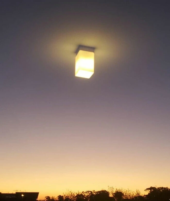 A glowing rectangular light fixture appears to float in a twilight sky above a dark horizon, making your brain question if it was edited.