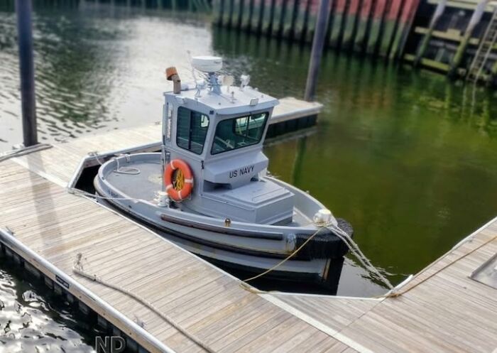 A tiny US Navy boat docked, appearing to be a real photo that makes you question if it was edited.