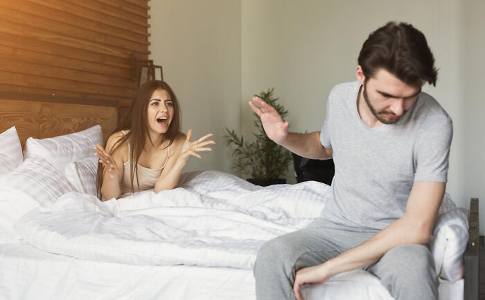 Couple arguing in bed, depicting a situation where red flags were ignored for someone hot.