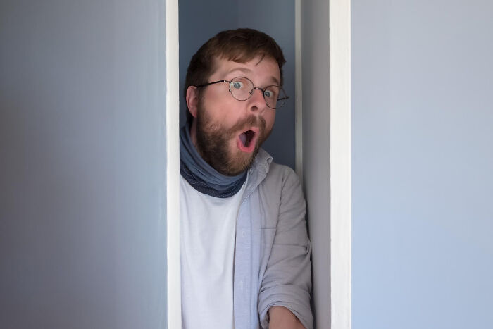 A man with great hair and a surprised expression, looking out from a doorway, illustrating ignored red flags.