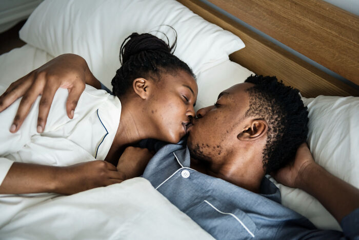 A couple kisses in bed, representing people who ignored red flags because the person was hot.