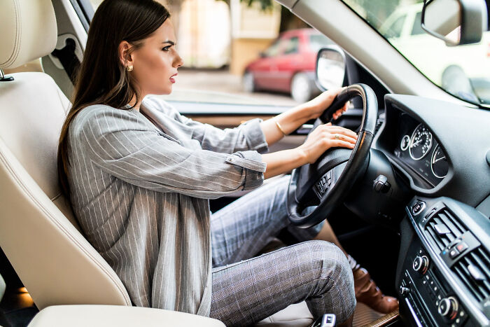 A woman with great hair and an angry expression, pressing the horn in her car, showing ignored red flags.