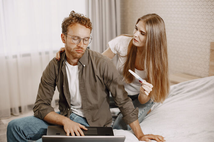 A man looking down at his laptop with a worried woman holding a pregnancy test, highlighting ignoring red flags.
