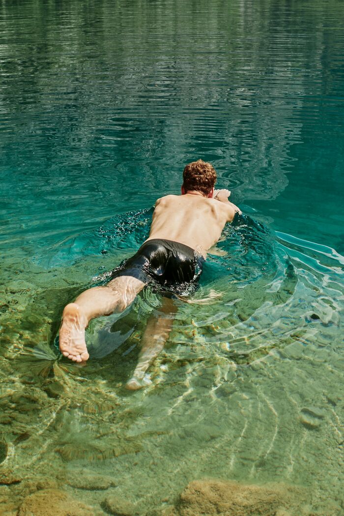 A man swimming in clear, shallow water, perhaps witnessing something disturbing.