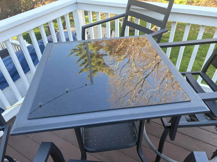 Outdoor table with a reflective black surface, showing tree reflections, seeking help fixing things and finding answers.