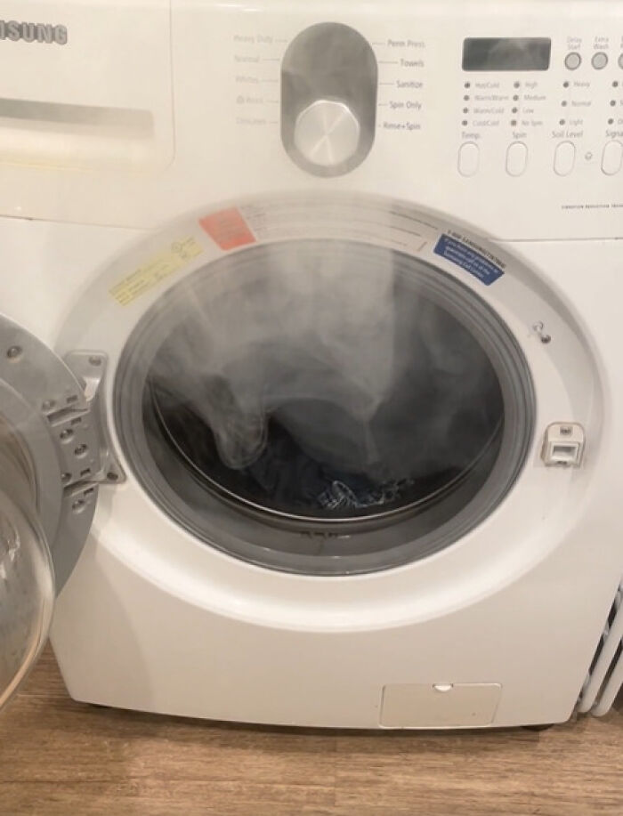 A front-loading washing machine emitting a lot of steam, indicating a problem that needs fixing.