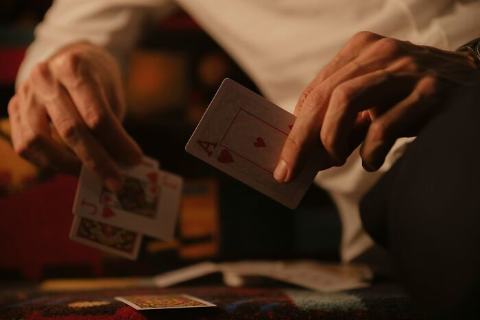 Hands holding playing cards, symbolizing the ways people are getting scammed without knowing it.
