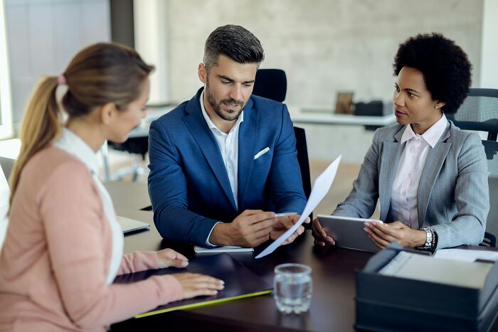 Businesspeople discussing documents, symbolizing various industries and how people are getting scammed by unscrupulous practices.