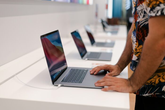 A person browsing laptops in a store, highlighting how people are getting scammed with electronics purchases.