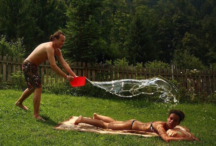 A man splashes water on a woman sunbathing, a hilarious photo taken moments before disaster struck.