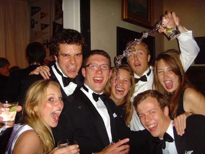 A group of friends laughing with a drink being spilled, a hilarious photo taken moments before disaster struck.