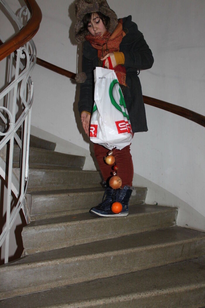 A woman on stairs drops groceries, captured in a hilarious photo moments before disaster strikes the produce.
