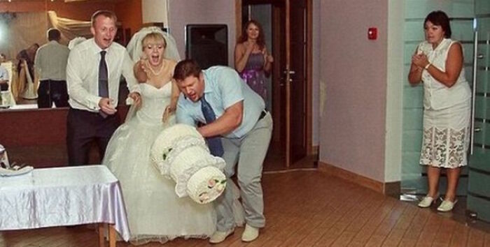 Hilarious photo of a wedding cake disaster, moments before the tiered cake falls to the floor.