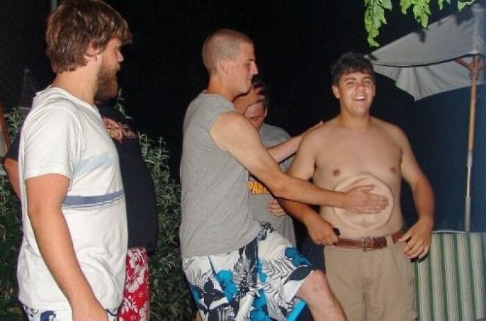 A man holds a plate over another man's stomach, a hilarious photo taken moments before disaster.