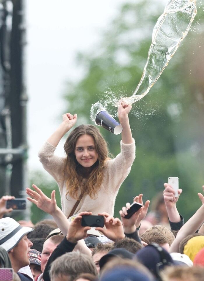 Hilarious photo of a girl at a concert smiling as a drink flies out of her cup moments before disaster struck.