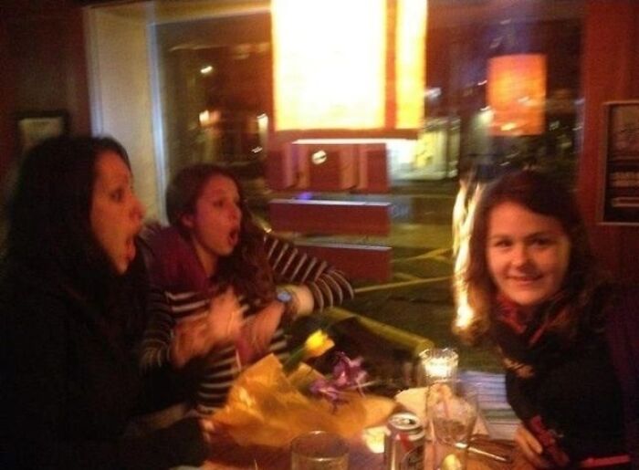 Hilarious photo of three women at a table, two reacting dramatically, taken moments before disaster.