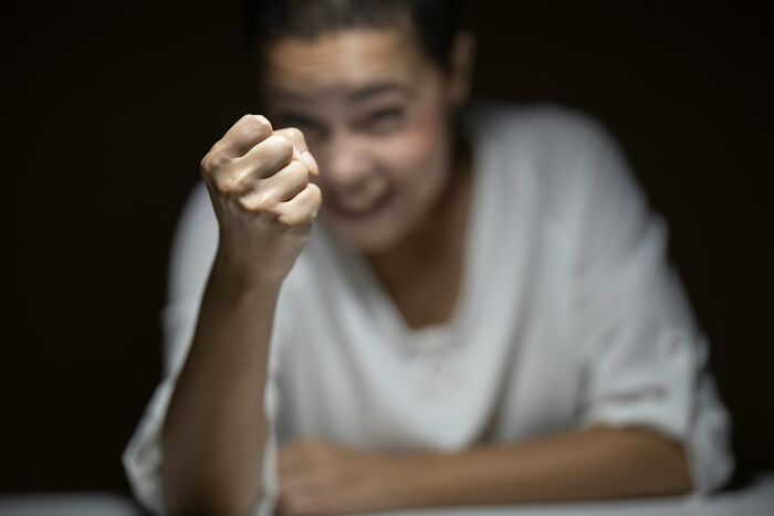 A person with a blurred face in the background, showing a clenched fist in focus, symbolizing psycho moments from partners.