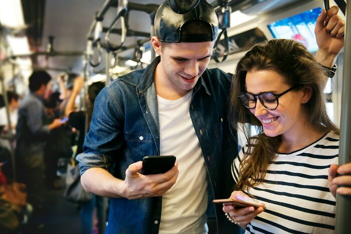 A couple on a train looking at their phones, possibly showing psycho moments from partners.