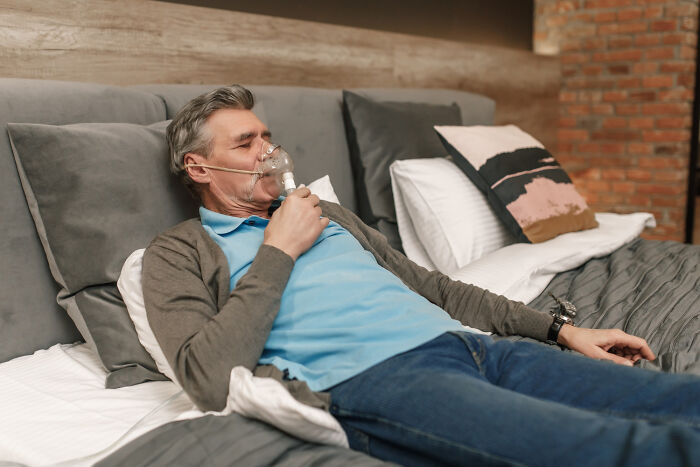An elderly man using an oxygen mask in bed, symbolizing challenges faced with partners.