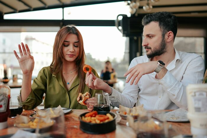 A woman at a restaurant refusing food from her partner, depicting psycho moments from partners.